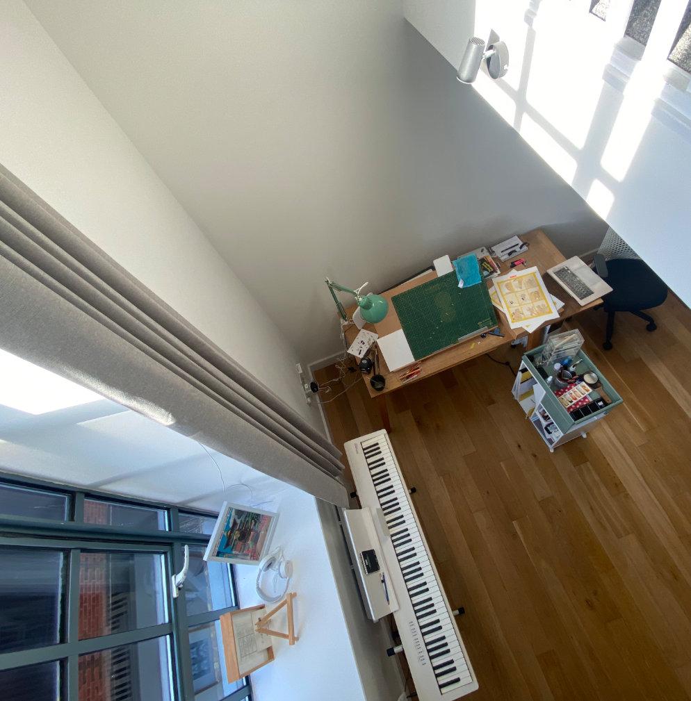 A photograph from the mezzanine of my new studio with an art desk and a piano